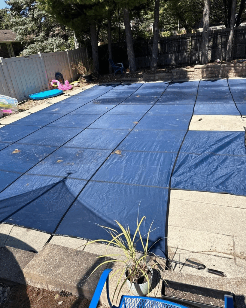 Backyard swimming pool covered with blue safety pool cover