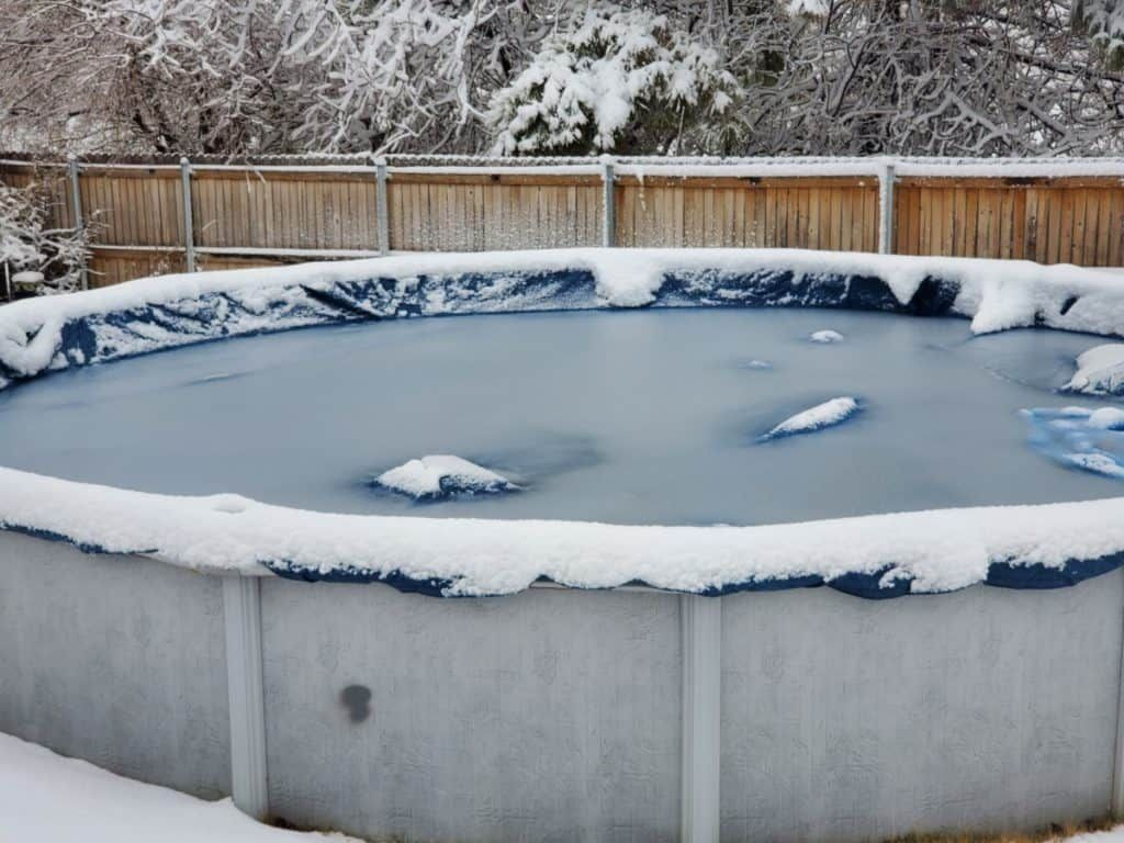 Above ground swimming pool frozen over with winter snow