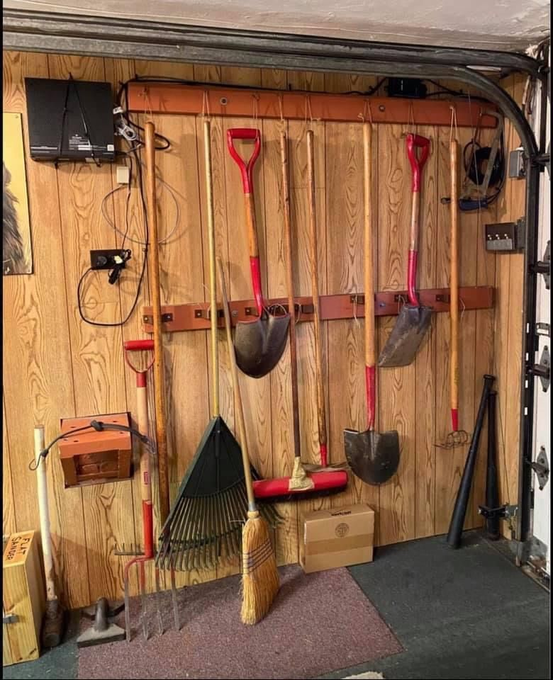 Organized garage wall with hanging shovels, rake, and broom