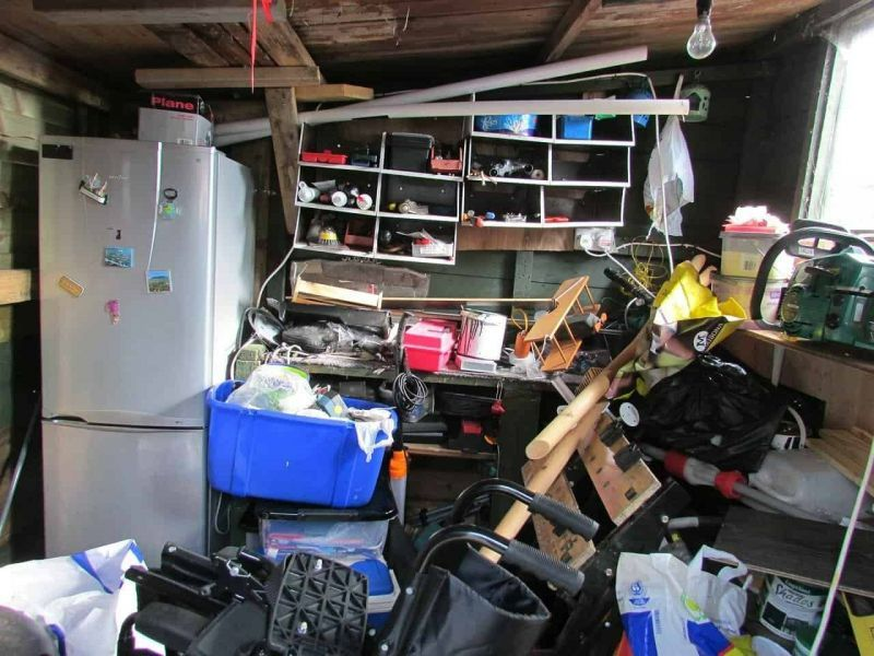 Cluttered garage workshop with disorganized tools and storage bins
