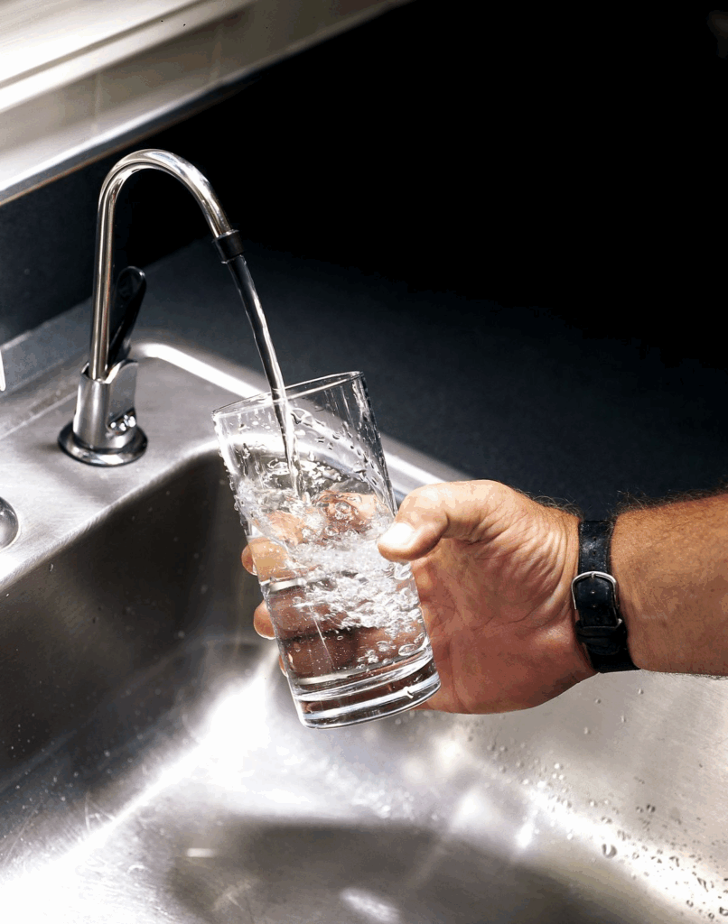 Hand filling glass with clean drinking water from faucet