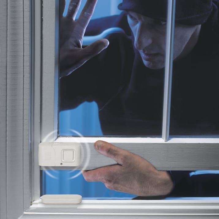Burglar attempting window break-in stopped by security alarm sensor